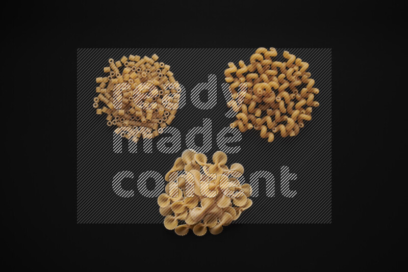Different pasta types in bunches on black background