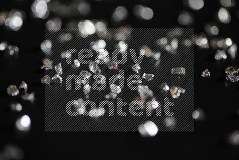 Silver shimmering fragments of glass scattered on a black background