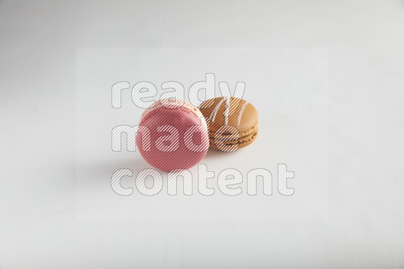 45º Shot of of two assorted Brown Irish Cream, and Pink Litchi Raspberry macarons on white background