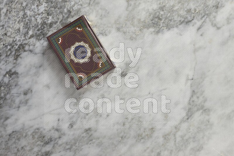 Quran with a prayer beads on grey marble background