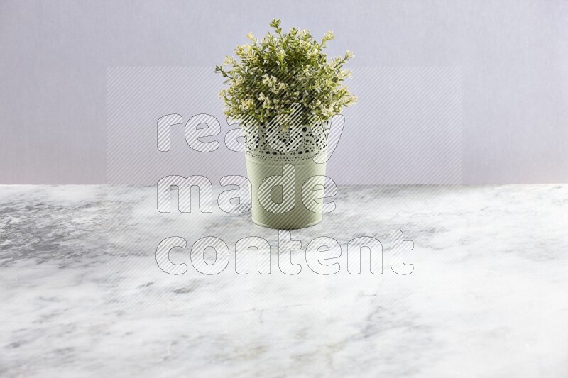 Artificial plant in green decorative pot on grey marble background