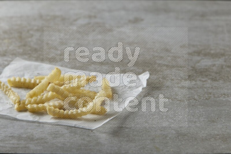 crinkle fries on parchment paper on grey textured counter top