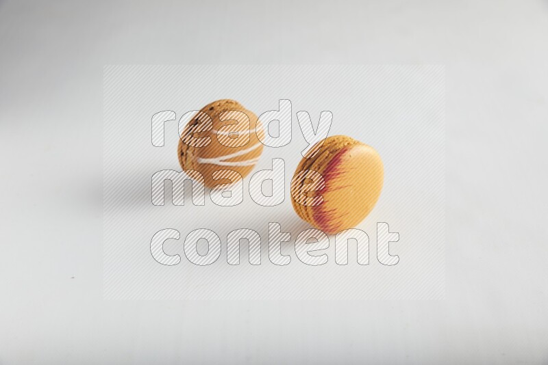 45º Shot of of two assorted Brown Irish Cream, and Orange Exotic macarons on white background
