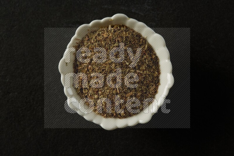 wooden round sauce bowl filled with herbs on grey textured countertop