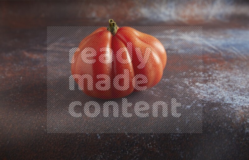 45 degree single heirloom tomato on  a textured reddish rustic metal background