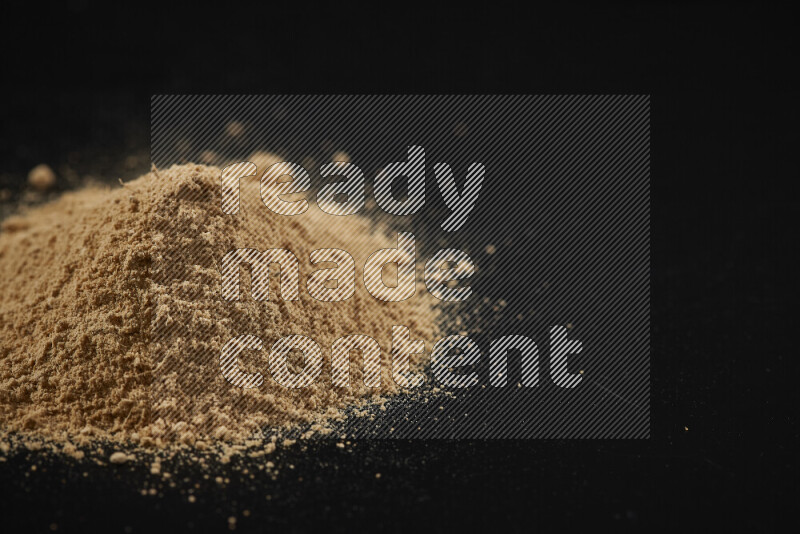 A bunch of ground ginger powder on black background