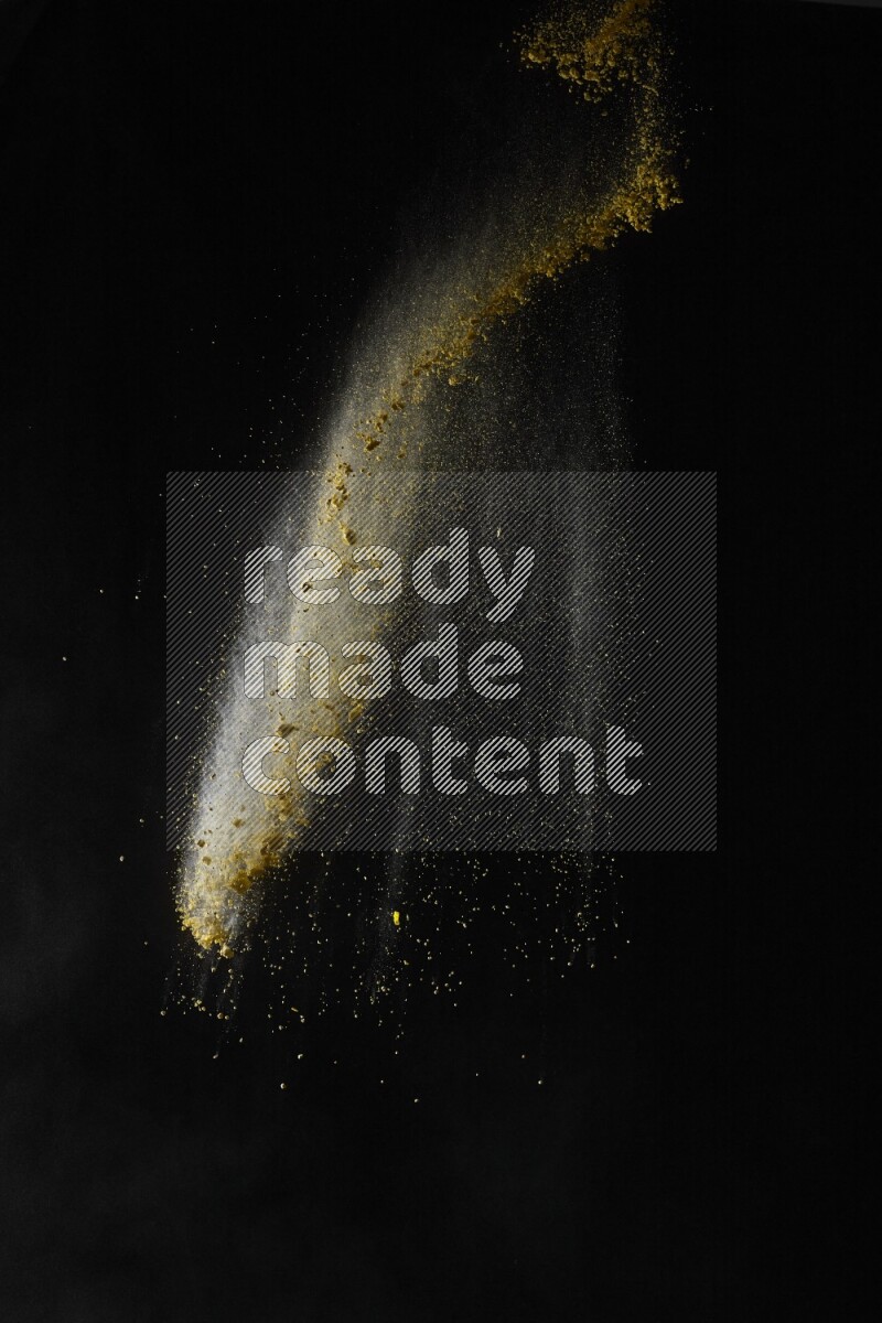 A side view of yellow powder explosion on black background