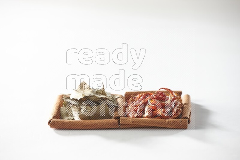 مربعان من أعواد القرفة ممتلئان بالفلفل الحار المجفف وأوراق الغار علي خلفية بيضاء