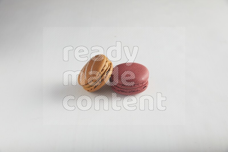 45º Shot of of two assorted Brown Irish Cream, and Red Velvet macarons on white background
