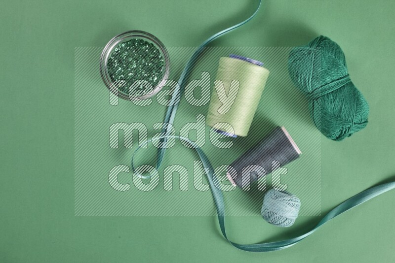 A green collection of sewing and tailoring tools arranged on a green background