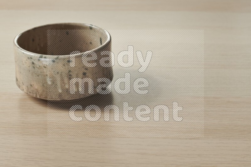 A multicolored pottery bowl on light wooden background
