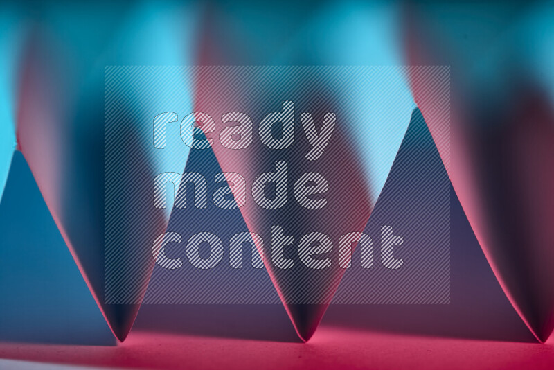 A close-up abstract image showing sharp geometric paper folds in blue and red gradients