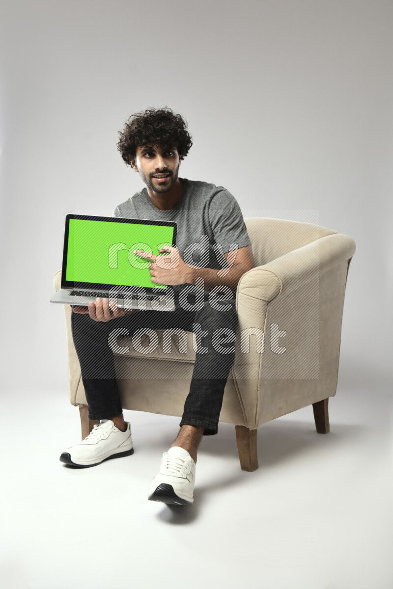 A man wearing casual sitting on a chair showing a laptop screen on white background