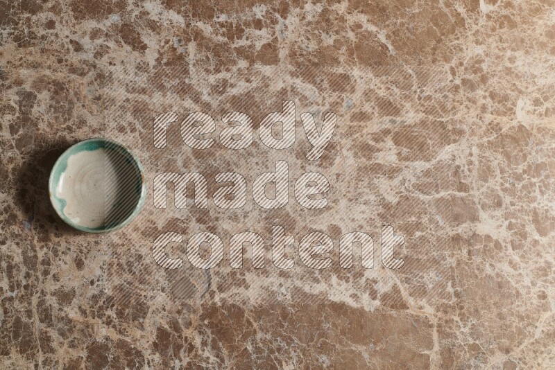 A multicolored pottery bowl on beige marble background