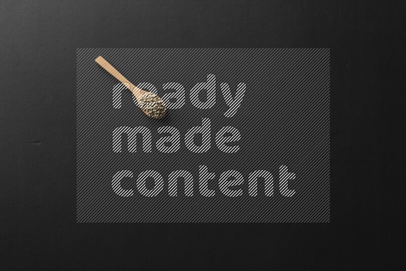 wooden spoons filled with white peppers, mustard seeds, black seeds, garden cress, cumin and flax on black flooring