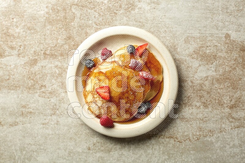 Three stacked mixed berries pancakes in a grey plate on beige background