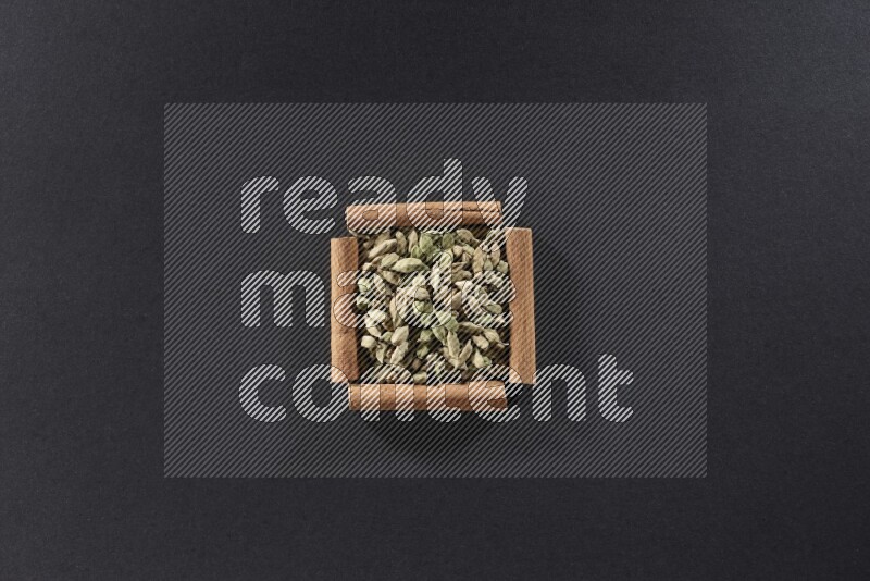 A single square of cinnamon sticks full of Cardamom on black flooring