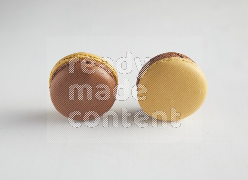 45º Shot of two Yellow and Brown Chai Latte macarons on white background