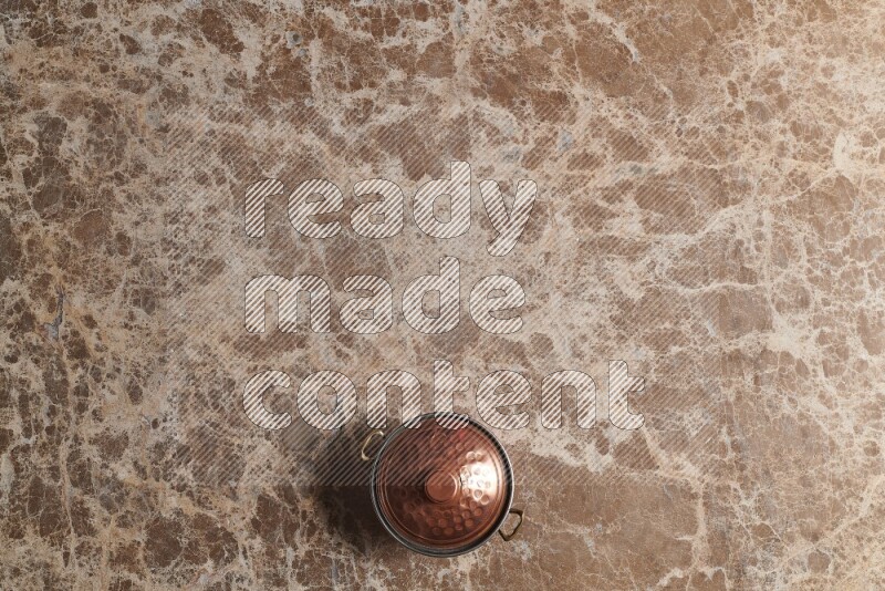 A small copper pot on beige marble background