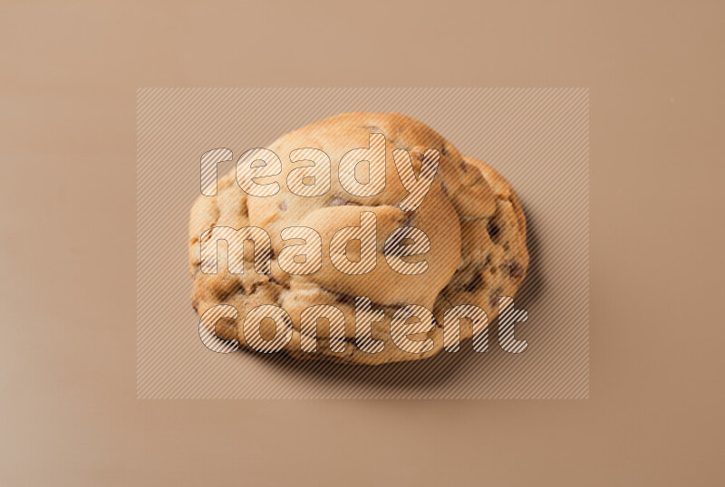 a whole chocolate chip cookie on a brown background