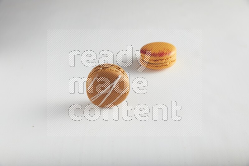 45º Shot of of two assorted Brown Irish Cream, and Orange Exotic macarons on white background