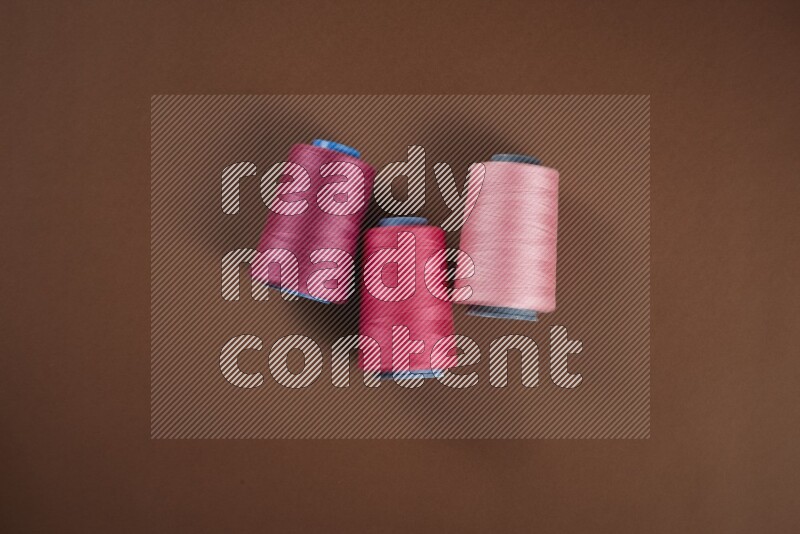 مجموعة من أدوات الخياطة والتفصيل زهرية اللون على خلفية بنية