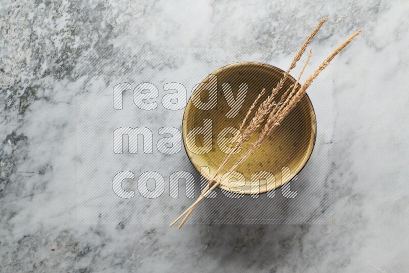 Wheat stalks on multicolored pottery oven plate on grey marble background