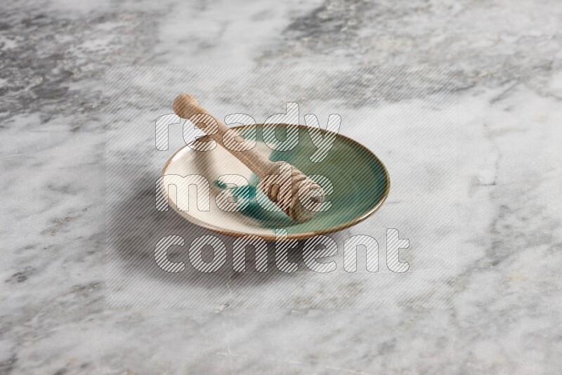 Multicolored pottery plate with wooden honey dipper in it on grey marble background