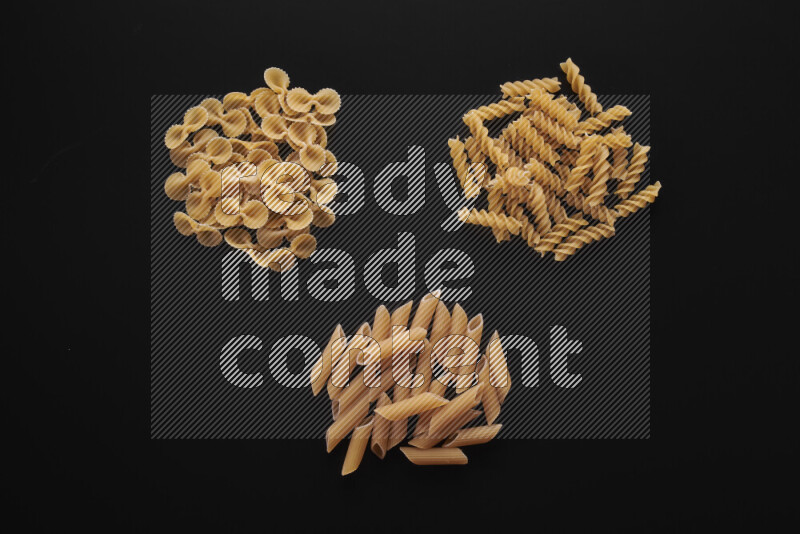 Different pasta types in bunches on black background