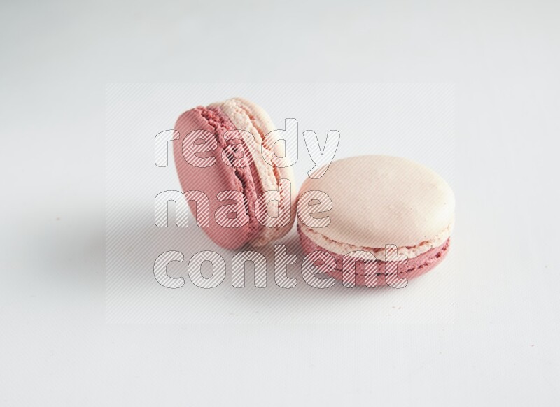 45º Shot of two Pink Litchi Raspberry macarons on white background