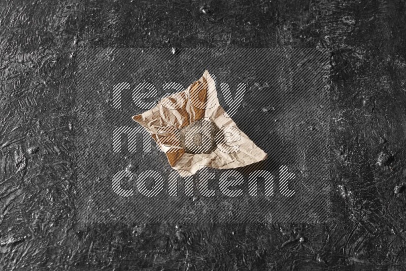 Black pepper powder on crumpled paper on a textured black flooring