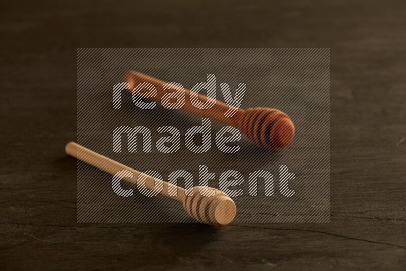 Wooden honey dipper on black slate background