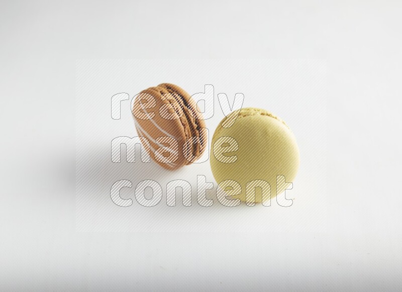 45º Shot of of two assorted Brown Irish Cream, and Yellow Lime macarons on white background