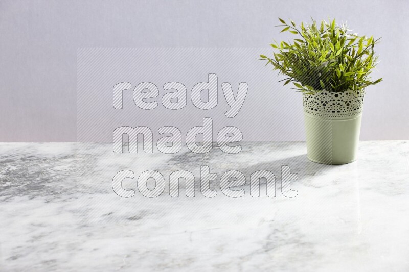 Artificial plant in green decorative pot on grey marble background