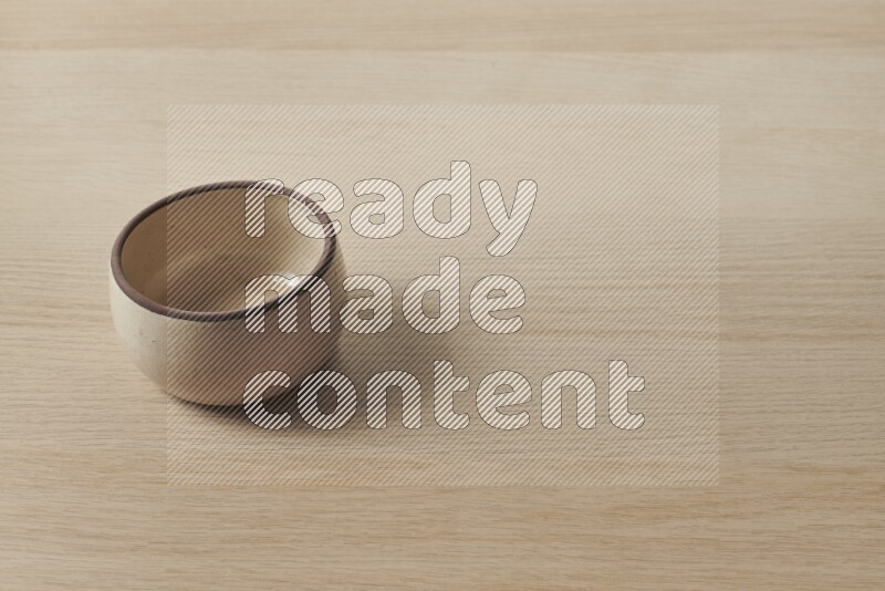 A beige pottery oven bowl on light wooden background