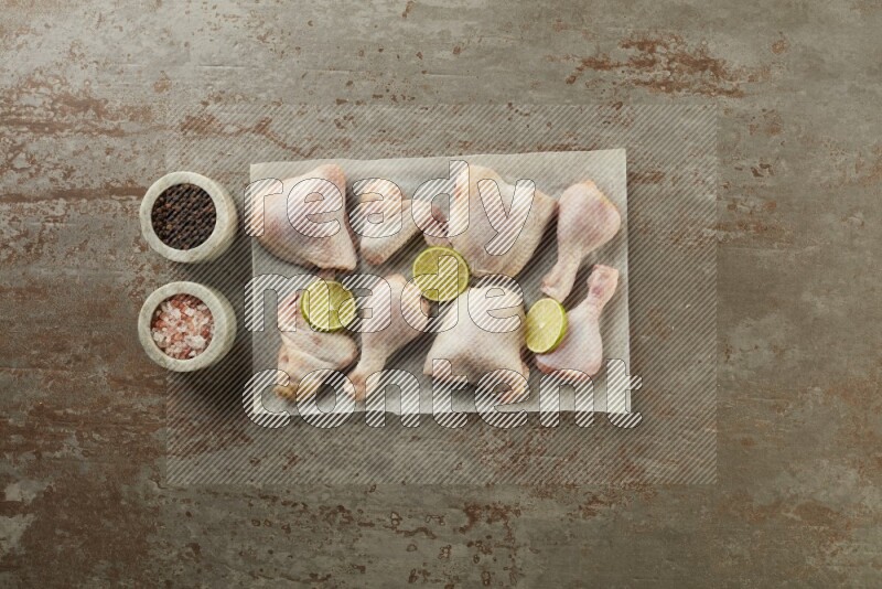 Mixed fresh chicken pieces on a parchment paper direct on a textured rustic background