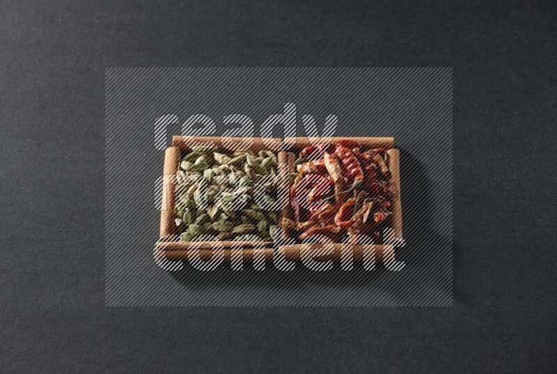 2 squares of cinnamon sticks full of chilis and cardamom on black flooring