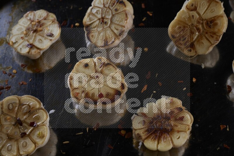 half's roasted garlic in a stainless tray on a grey textured countertop