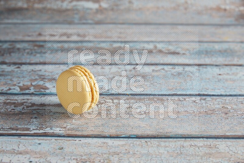 45º Shot of Yellow Vanilla macaron on light blue wooden background