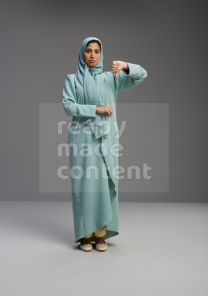 Saudi Woman wearing Abaya standing interacting with the camera on Gray background