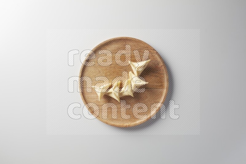 Five Sambosas on a wooden round plate on a white background