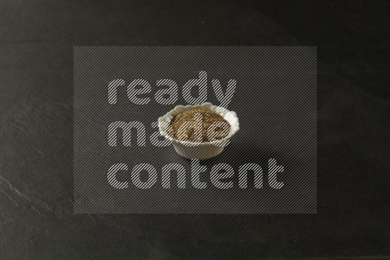 white ceramic round sauce bowl filled with herbs on grey textured countertop