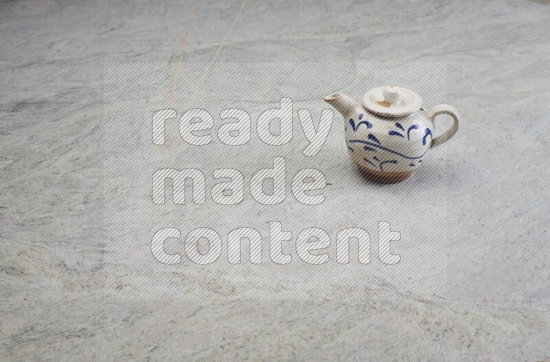 A pottery teapot on grey marble background