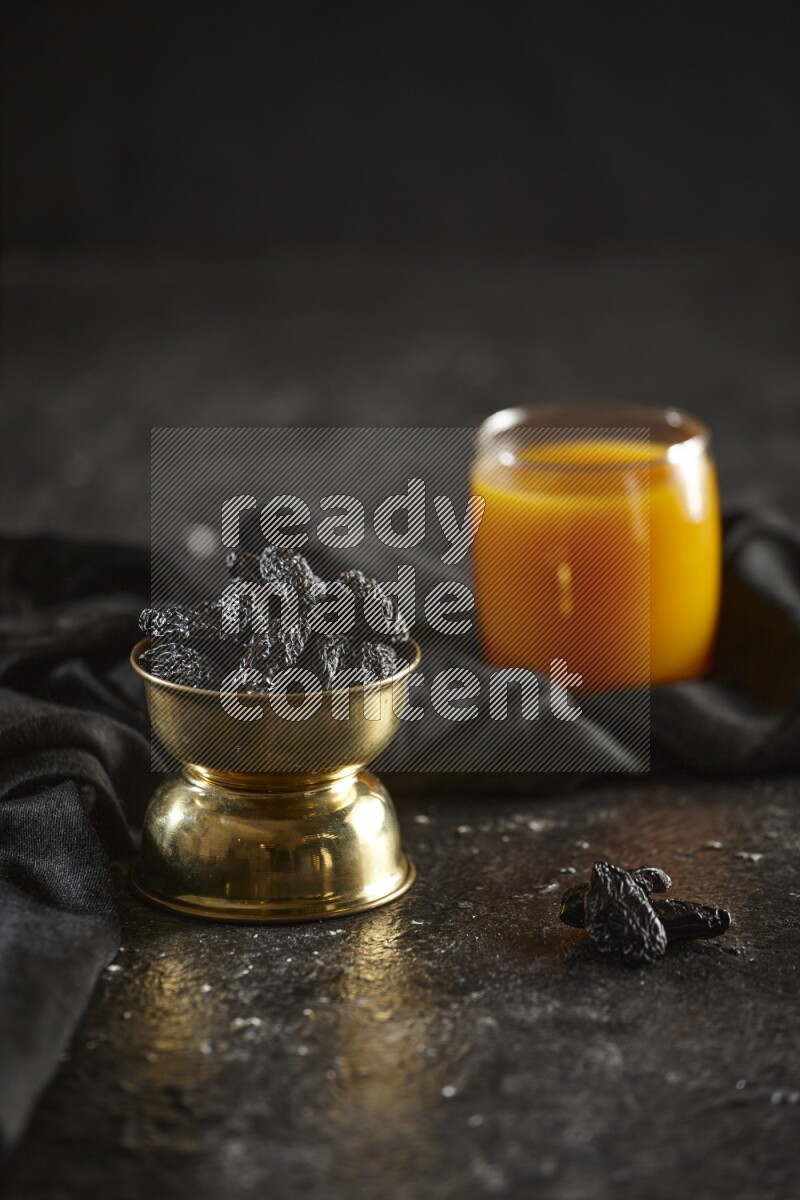 Dried fruits in a metal bowl with qamar eldin and a napkin in a dark setup