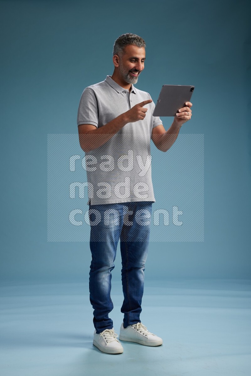 Man Standing working on tablet on blue background