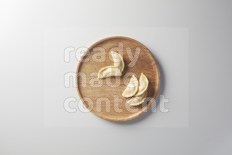 Five Sambosas on a wooden round plate on a white background