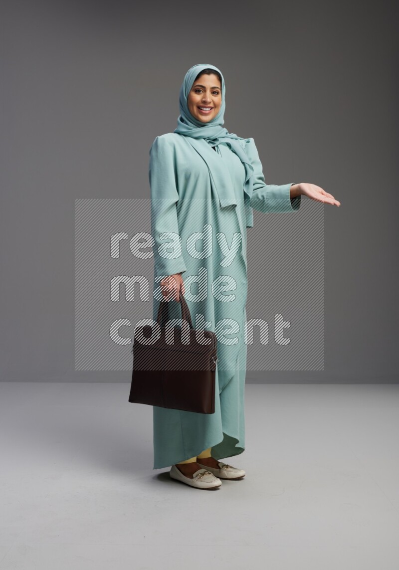 Saudi Woman wearing Abaya standing holding bag on Gray background