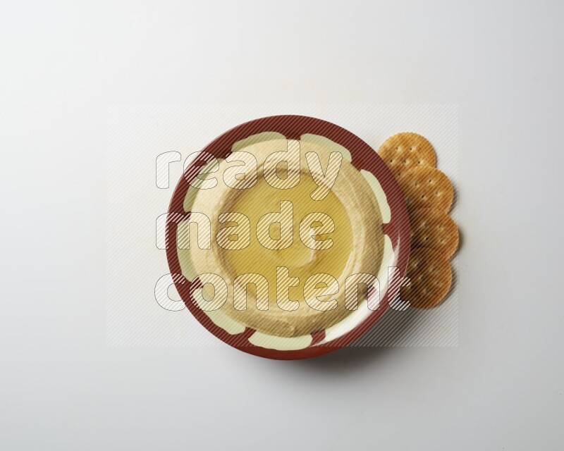 Hummus in a traditional plate garnished with olive oil on a white background