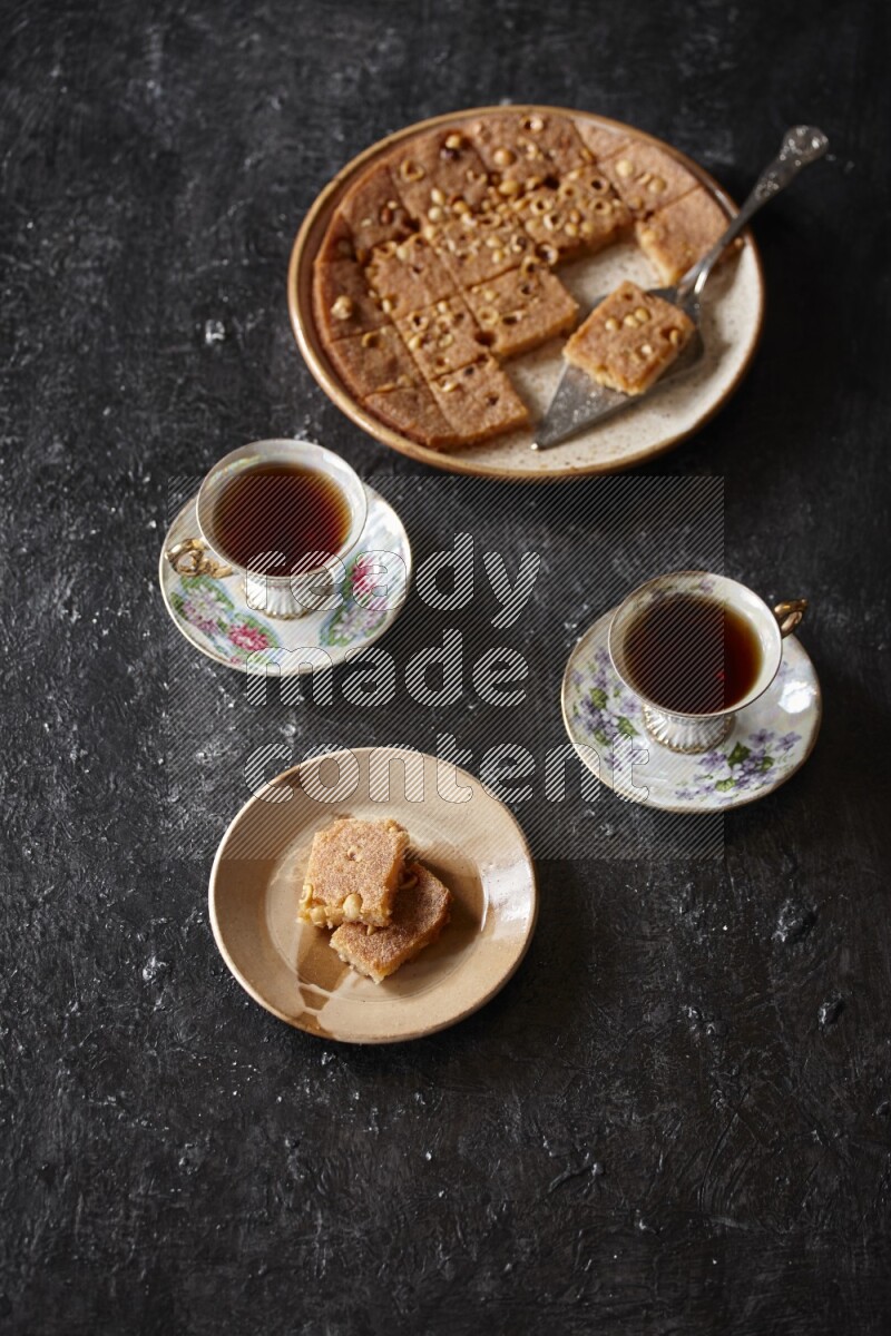 Basbousa with tea in a dark setup