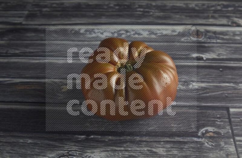 45 degree single heirloom tomato on a textured grey wooden background